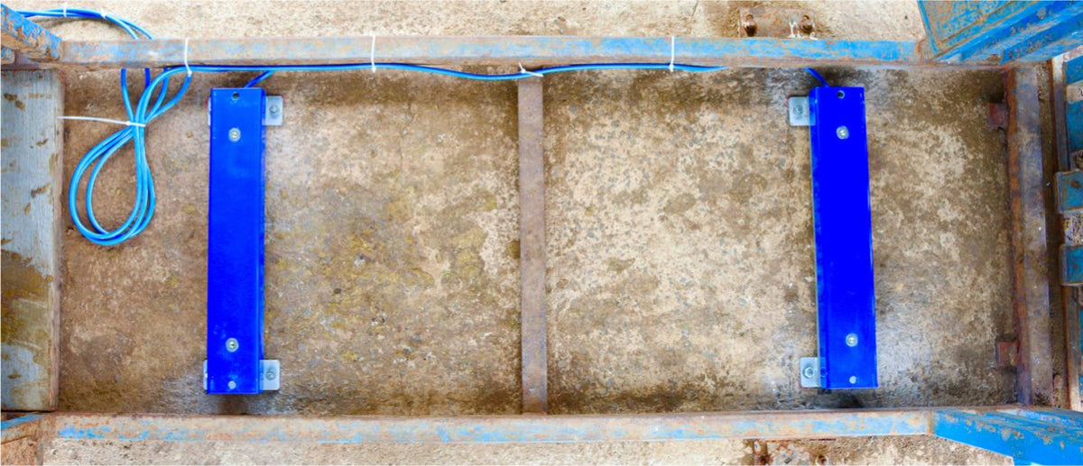 Two load bars fixed to a concrete pad inside a crush with dynabolts